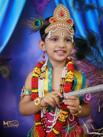 A close-up portrait highlighting the beautiful details of the Krishna costume and the child's infectious smile. A perfect photo for the festive season.