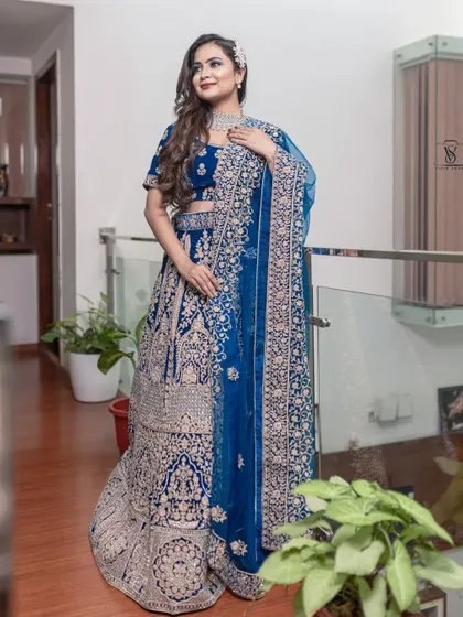 A full view of the magnificent peacock blue bridal lehenga, showcasing the intricate embroidery that covers the entire skirt and blouse.