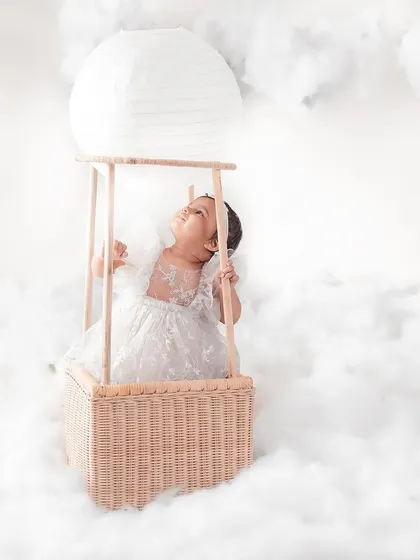 Like a little dream. This baby angel, dressed in white and floating in a basket among the clouds, creates such a serene and heavenly portrait.
