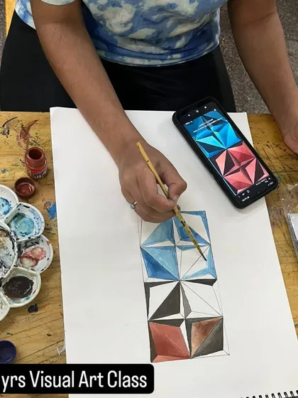 This student is working on a geometric abstraction piece, learning about precision, color theory, and creating a sense of 3D form on a 2D surface.