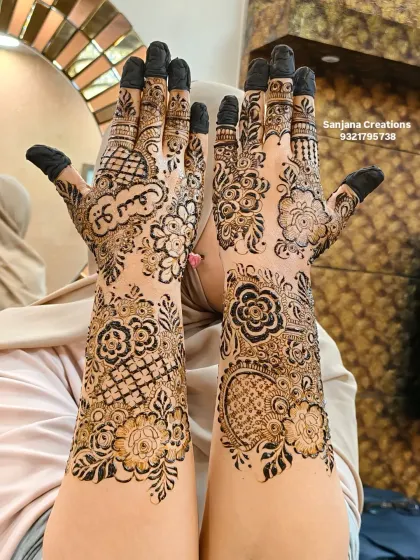 A happy client showing off her intricate Dubai-style bridal mehndi, personalized with her partner's name in Arabic.