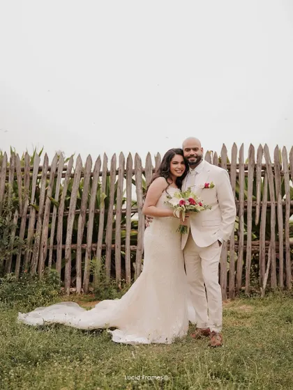 A classic wedding portrait of the bride and groom against a rustic wooden fence, a timeless image from their special day.
