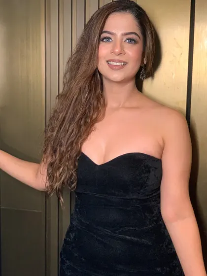 A confident pose in the black velvet gown. The simplicity of the dress allows the focus to be on the host.