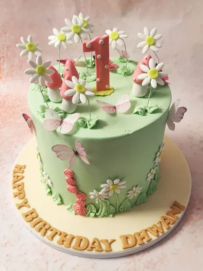 We create an enchanted forest for a first birthday with this magical fairy cake. A lush green canvas is home to whimsical mushrooms, delicate daisies, and fluttering butterflies, creating a storybook setting for a one-year-old's special day.