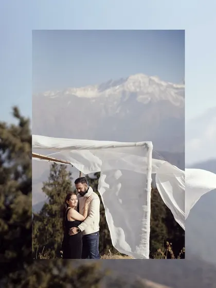 An artistic shot of a couple framed by a white canopy, with the Himalayas in the distance. This composition highlights both the couple and the majestic scenery.