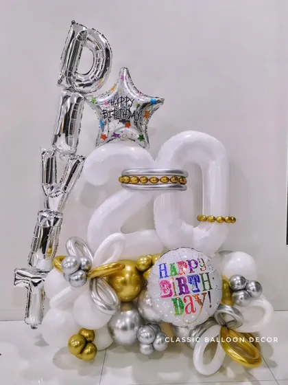 A personalized balloon bouquet for a 20th birthday, with the name 'DIVIT' in foil letters and a mix of gold, silver, and white balloons.