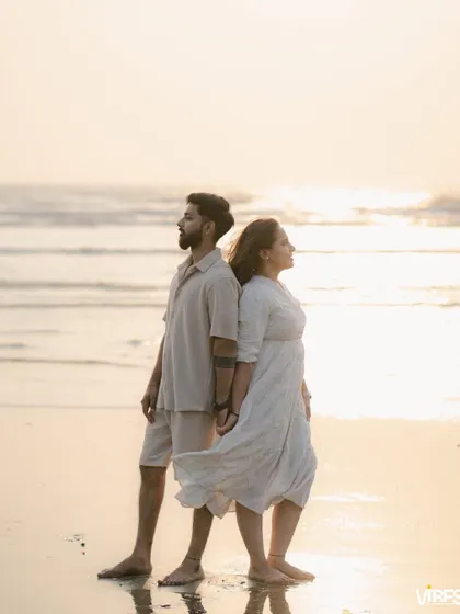 A posed shot of a couple standing back-to-back on the beach, looking out at the ocean as the wind blows through her hair. This captures a feeling of quiet strength and partnership.