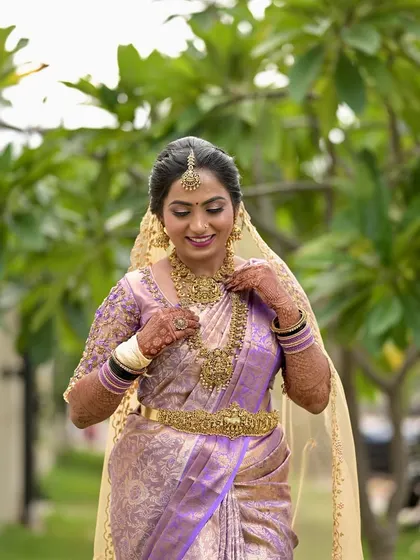 A candid moment of the bride adjusting her necklace. Her makeup looks soft and beautiful, with a gentle glow to her skin.