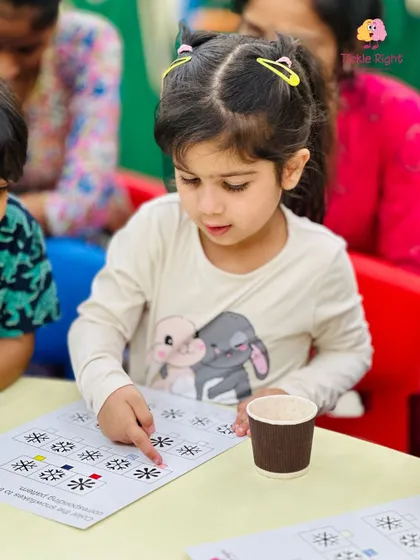 A young girl carefully analyzes a pattern recognition worksheet. Activities like this are designed to sharpen visual discrimination and logical thinking skills.