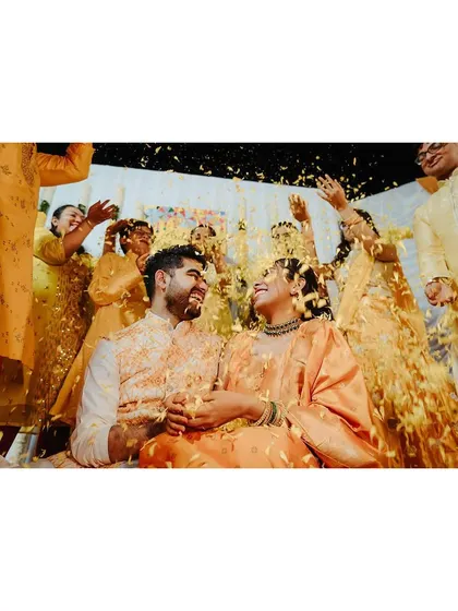 The couple looking at each other amidst a rain of flowers, a magical and romantic Haldi moment.