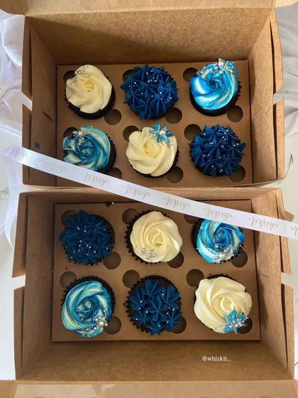 A beautiful assortment of blue and white cupcakes. The different piping techniques, from rosettes to star tips, create a visually interesting and elegant box.