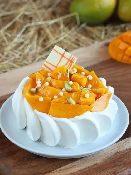 This mini mango cake is a personal indulgence. It's topped with a generous amount of fresh mango chunks and pistachio slivers, offering a burst of flavor in every bite.