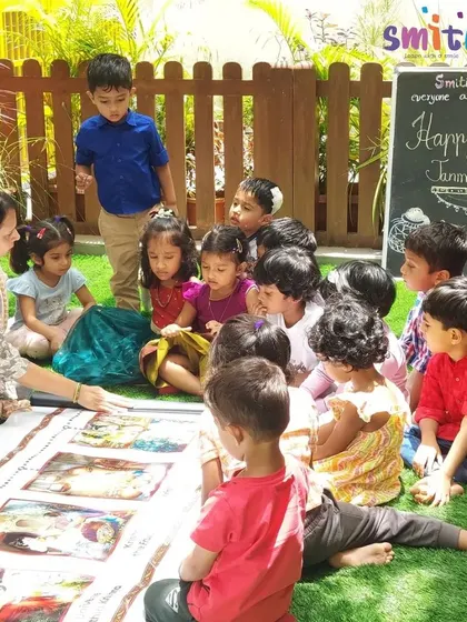 A group of children gathers around their teacher and a story scroll, learning about the tales of Janmashtami. This interactive format encourages questions and discussion.