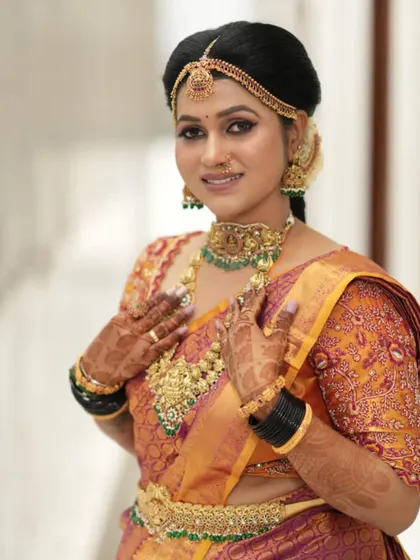 This bride is the picture of grace. The complete temple jewellery set adds a regal touch to her beautiful orange and purple silk saree.