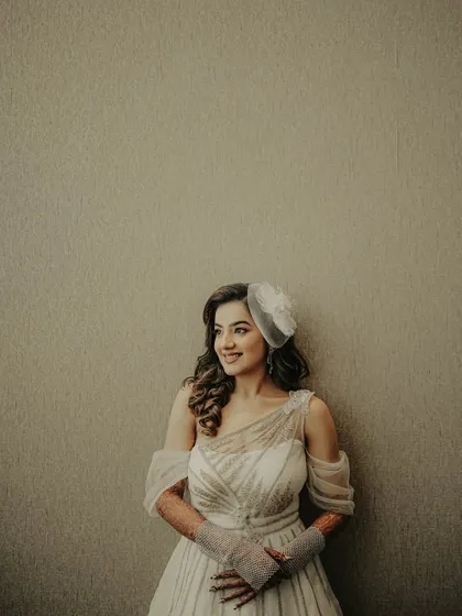 A simple and elegant bridal portrait. The minimalist background puts all the focus on the bride, her beautiful smile, and her chic white gown with a fascinator.