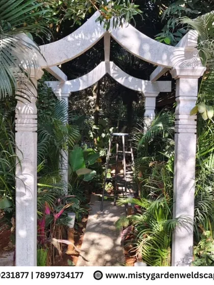 The completed natural stone archway, creating a beautiful and grand entrance to a garden path, surrounded by lush tropical foliage.