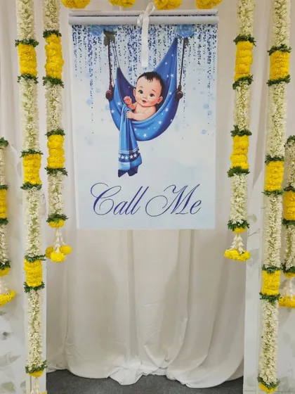 The "Call Me" banner is a sweet and playful touch for a naming ceremony, building anticipation for the big reveal. We framed it with traditional flower garlands to blend it seamlessly into the overall decor.