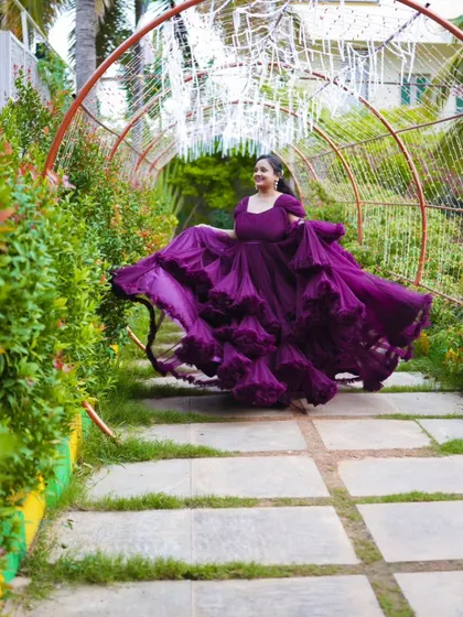 A beautiful shot of the bride-to-be in a flowing purple gown, creating a sense of movement and elegance in a garden pathway.