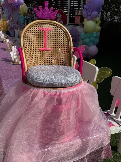 A special throne for the birthday princess, complete with a sparkly silver seat, a pink tutu skirt, and a glittery crown on top.