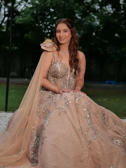 This wedding season, wear designer without disturbing your budget. A client looks stunning in a beige ball gown with a feathered shoulder detail, available for rent.