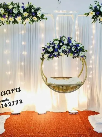 A simple and elegant cradle ceremony setup. The clean white drapes are accented with corners of white and blue flowers, creating a serene and beautiful backdrop for the occasion.