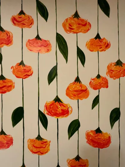 A detailed view of the hanging marigold mural. The simple lines and vibrant orange and yellow hues create a cheerful and traditional look.