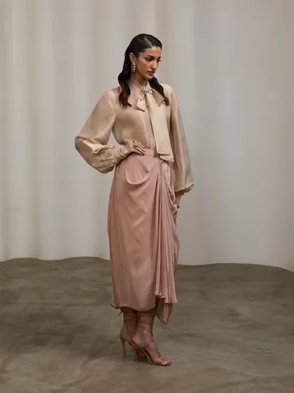 A profile shot showing the full length and flow of the draped skirt. This angle provides a different perspective on the outfit, highlighting its structure and how it moves with the body.