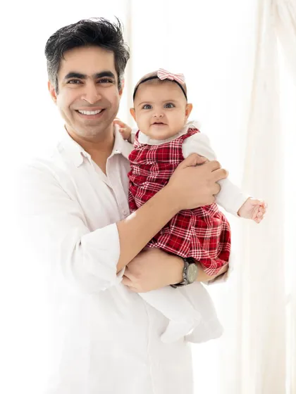 A proud father holding his adorable baby girl. This simple, high-key portrait is all about the connection and love between a dad and his daughter.