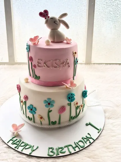 This two-tier cake features a cute bunny in a field of flowers. It's a fully fondant-covered cake, which allows for a very clean and smooth storybook finish.