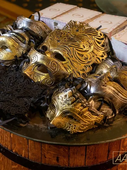 In true speakeasy style, every guest received a masquerade mask upon entry. This collection of ornate gold, silver, and black masks was displayed on a rustic barrel, adding to the theme's authenticity.