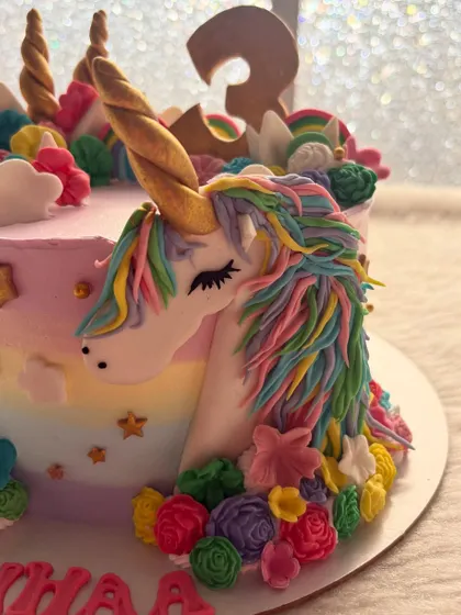 A close-up of the handcrafted unicorn on the cake. I love creating the rainbow mane with individual strands of colored frosting.
