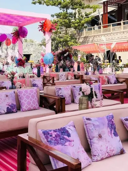 Guest seating at a luxurious outdoor Mehendi, with comfortable sofas and printed cushions in a beautiful pastel purple color scheme.