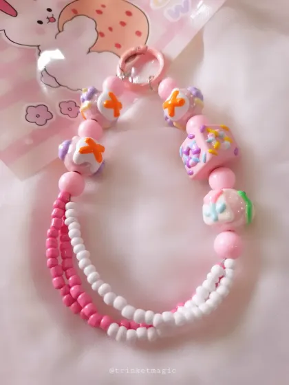 A pink and white version of my cake-bead charm. The combination of pink, white, and orange accents gives it a sweet, candy-like feel.