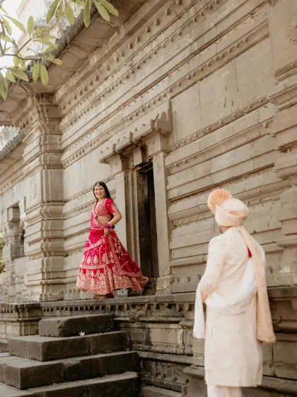 The first look. The groom watches as his bride, in her stunning red lehenga, descends the temple steps. A truly cinematic moment.