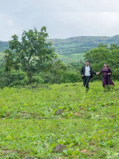 A playful, action shot of the couple running through a green field, capturing their fun-loving spirit and the joy of being together.