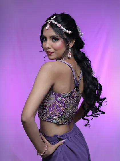 A modern party look with a purple outfit and intricate diamond jewelry. The hairstyle is a chic braided ponytail, perfect for dancing the night away.