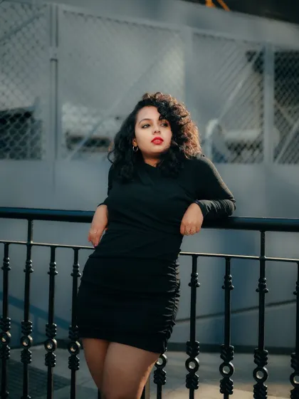 A portrait that plays with light and shadow on the street. The model's pose against the railing and the cool color palette create a sophisticated urban look.