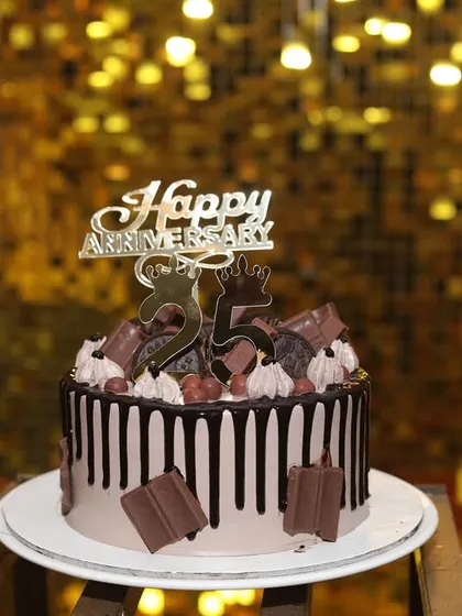 The delicious-looking anniversary cake, perfectly positioned to be the star of the show against the sparkling gold backdrop.