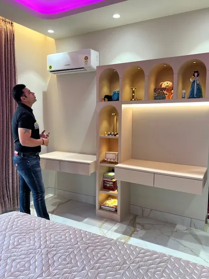 A completed kid's bedroom with a dual study table and a custom shelving unit with arched niches and internal lighting.
