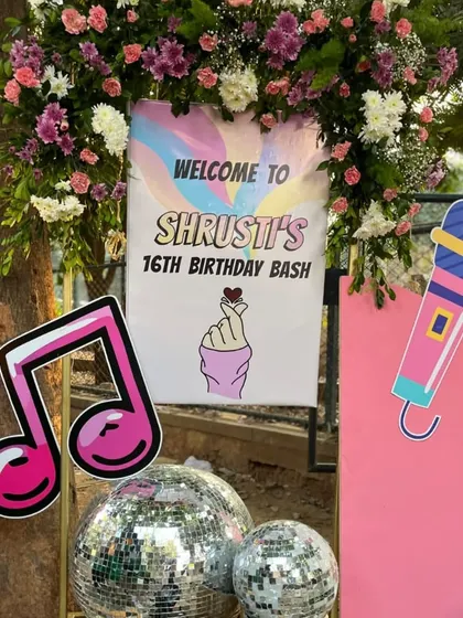 A welcome sign for a K-Pop themed 16th birthday. The sign features a microphone, a music note, and the iconic "finger heart" gesture, setting the tone for a music-filled celebration.