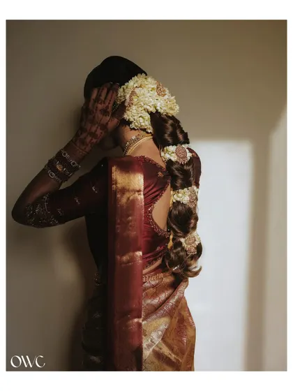 An artistic shot focusing on the bride's intricate hairstyle, adorned with fresh jasmine flowers, and her henna-covered hands.