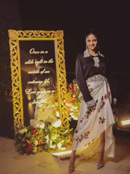 A guest poses with a custom mirror I designed for a 30th-anniversary party. The mirror is inscribed with the quote, "Once in a while, right in the middle of an ordinary life, Love gives us a fairytale."