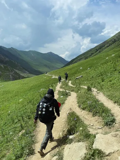 The trail winds through the vibrant green meadows of Kashmir. This photo captures the feeling of freedom and exploration on the KGL trek.