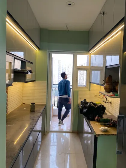 A work-in-progress shot of a parallel kitchen. This view shows the spaciousness and the natural light coming in from the balcony.