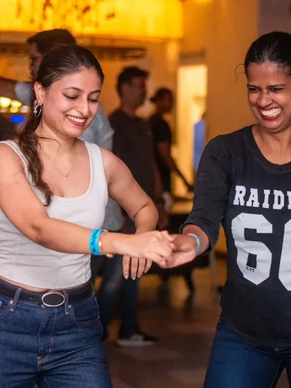 Two friends dancing together and smiling.