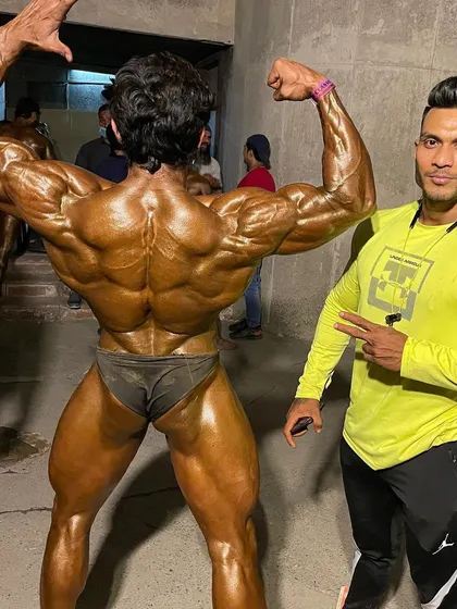 Backstage, a client showing his incredible back development before hitting the stage.