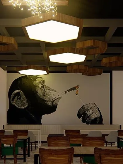 The interior of a pub I designed in Nagarbhavi. The space features custom hexagonal lighting fixtures, a coffered ceiling, and bold wall art to create a unique and moody ambiance.