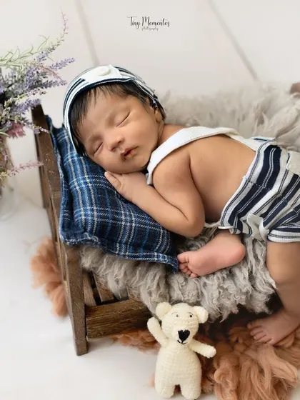 Eat, sleep, snuggle, repeat. This little one is enjoying a peaceful nap on a miniature bed, dressed in a charming striped outfit.