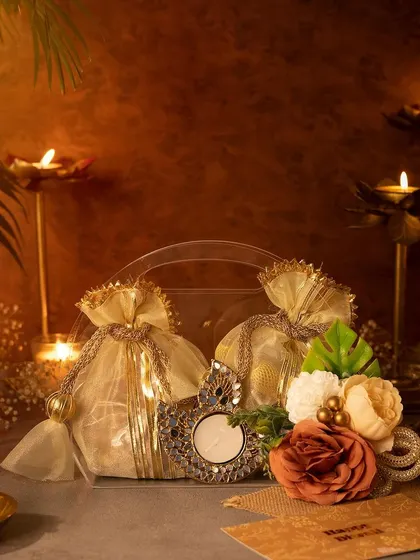 A unique and beautiful Diwali gift option. This clear, handled bag is decorated with flowers and contains festive potlis and a decorative T-light holder, offering a modern twist on traditional gifting.