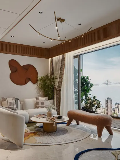 This sea-facing living room is designed to maximize the stunning view. We used a neutral color palette with pops of orange, custom furniture, and a unique wooden art piece to create a warm, cozy feel without distracting from the Bandra-Worli Sea Link outside.